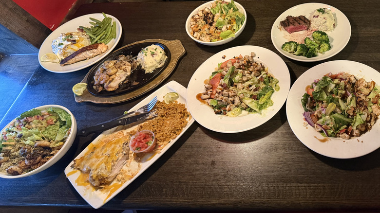 Eight plates of partially eaten food lined up on a table
