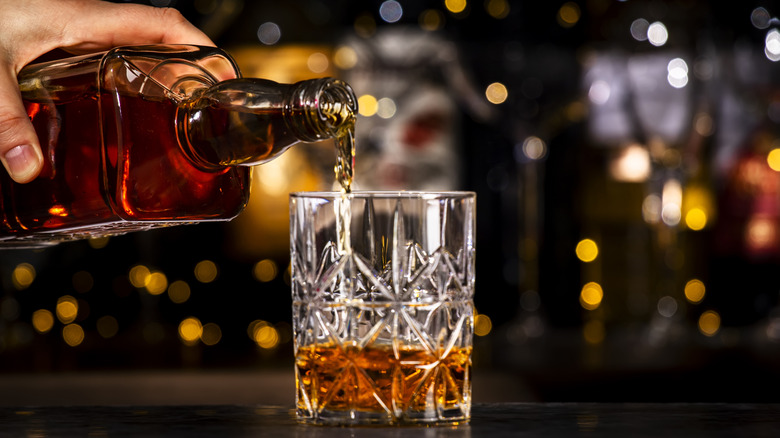 Hand pouring whiskey into a highball glass