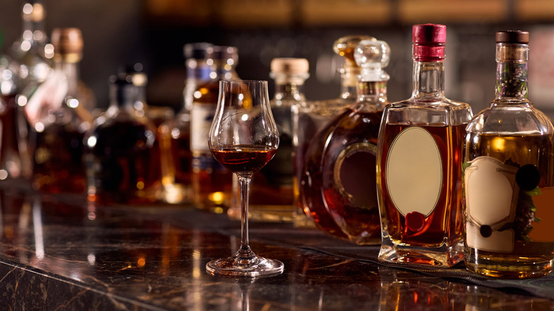 Nondescript bottles on a bar top with a tulip glass full of cognac