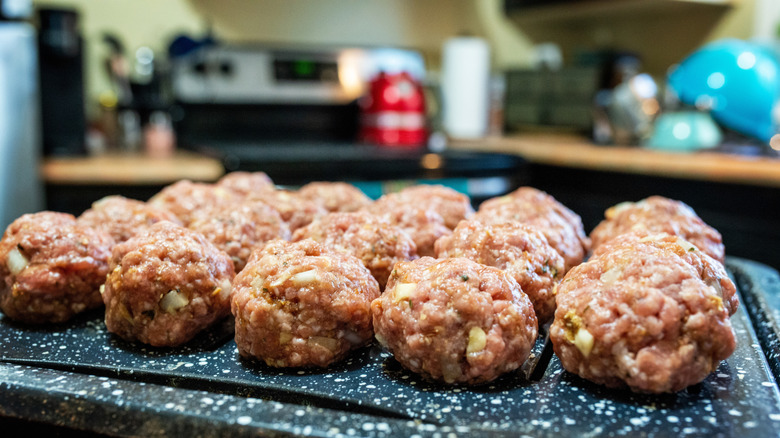 A tray full of uncooked meatballs