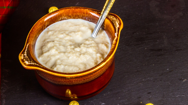 A pot of bread sauce on a board with a spoon