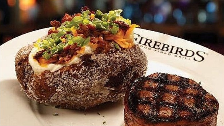 Closeup of a salt-crusted loaded baked potato at Firebirds Wood Fired Grill