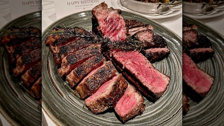 Two New York strip steaks are cooked rare on a green plate at Fleming's
