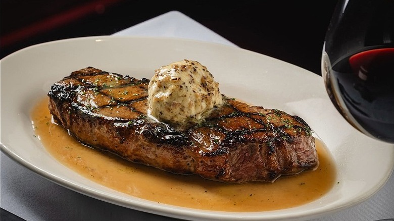 Closeup of a New York strip steak with compound butter at Morton's the Steakhouse