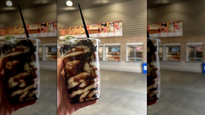 Hand holding a Costco Double Chocolate Mint Sundae with the food court in the background