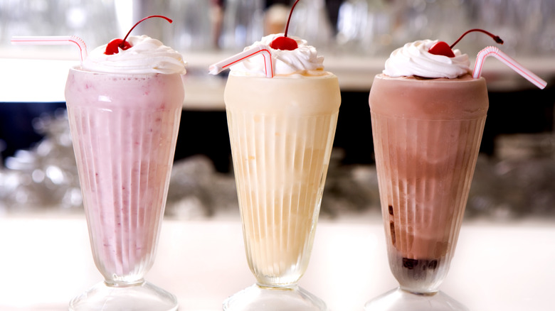 Three malted milkshakes on a countertop