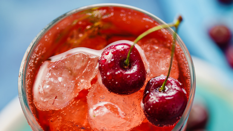 A cherry soda over ice topped with cherries