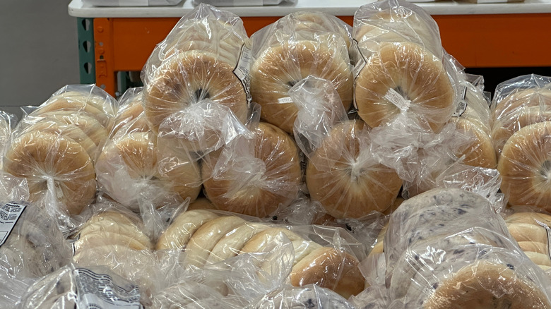 Bags of bagels are piled together on a table in a Costco bakery