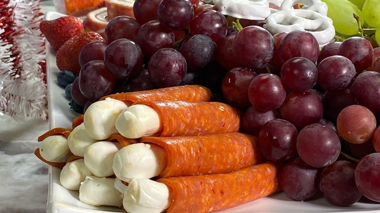 Formaggio Artisan cheese wraps sit on a plate of fresh fruit and pretzes