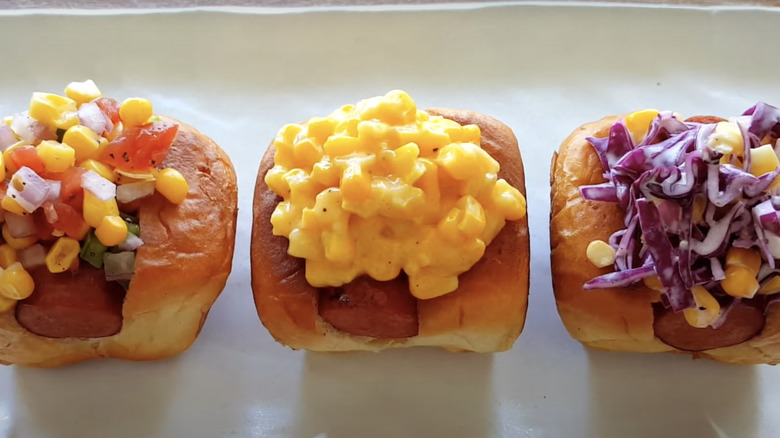 Three hot dog sliders with various corn-based toppings