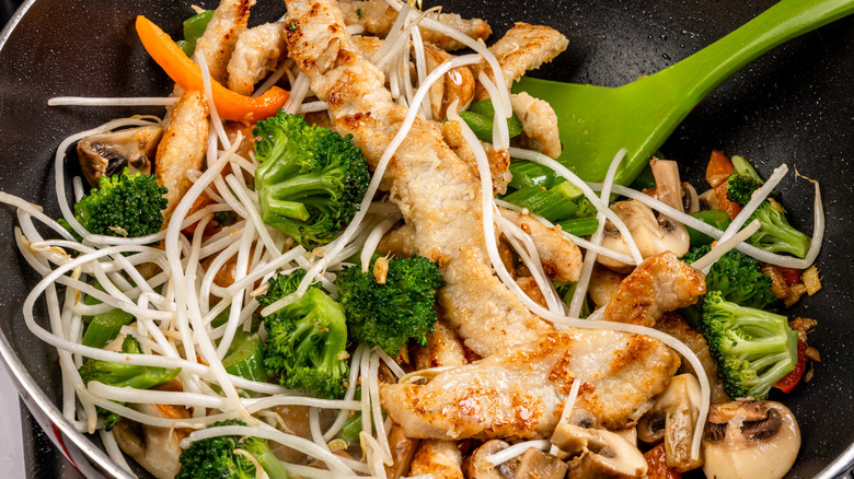 Pan full of stir-fried broccoli, chicken, sprouts, and mushrooms