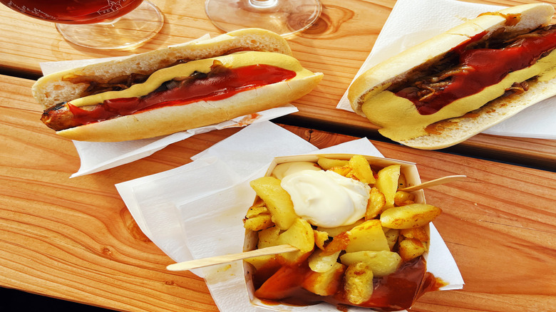 Hot dogs with ketchup and mustard next to glasses of beer
