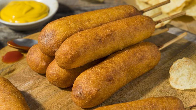 Pile of corndogs next to bowl of mustard
