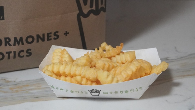 Shake Shack French fries in front of a brown paper Shake Shack bag.