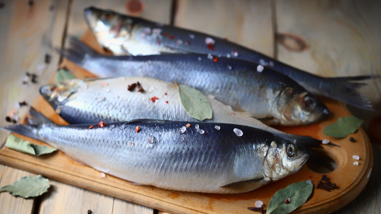 whole salted herring on wooden board 