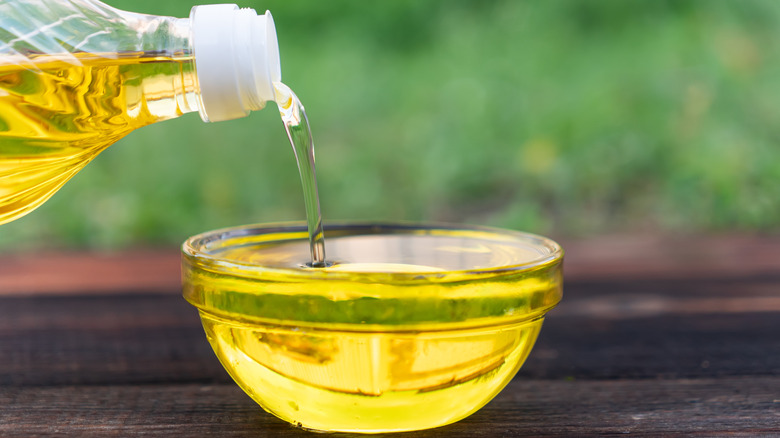 Pouring canola oil into a small glass bowl.