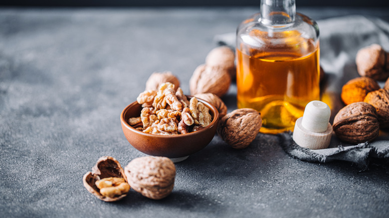 Walnuts next to a bottle of oil.