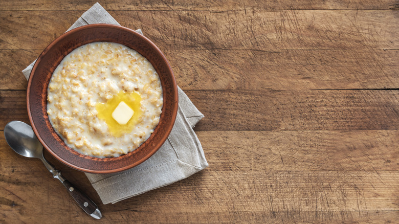 A bowl of oatmeal with a pat of butter melting in it.