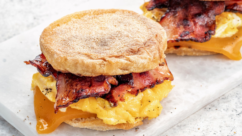 Two English muffin breakfast sandwiches sit on a piece of white marble.