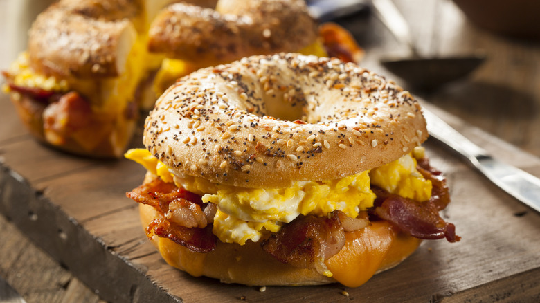 Two bagel breakfast sandwiches sit on a wooden table.