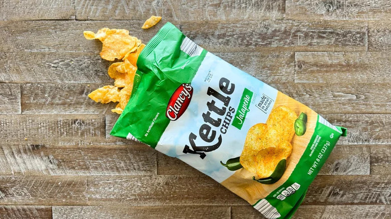 A bag of open Clancy's Jalapeño Kettle Chips rests on wooden surface