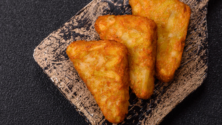 triangular golden brown hash browns on dark background