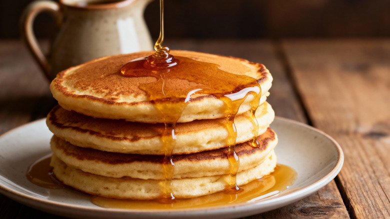 stack of pancakes getting drizzled with syrup