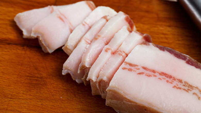 slices of salted pork on wooden cutting board
