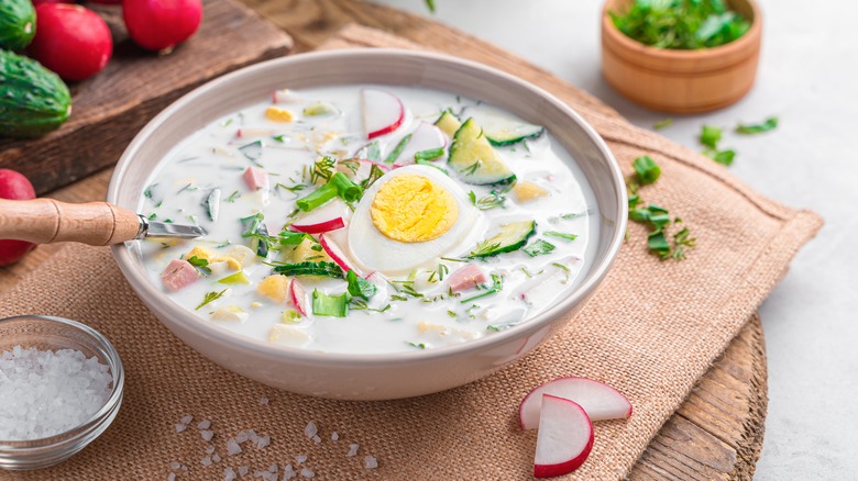 Okroshka with egg garnish on tablecloth