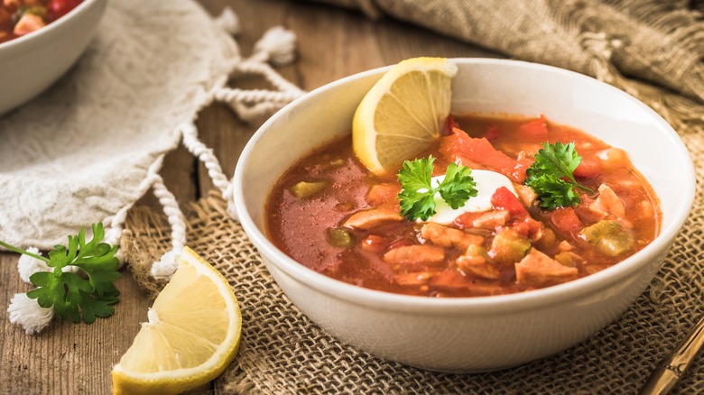 Solyanka with lemon wedges served in white bowl
