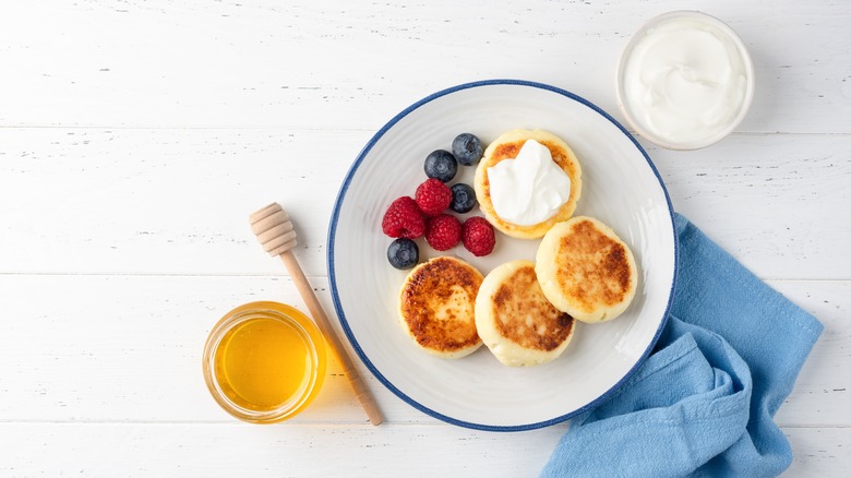 Syrnyky with sour cream, honey, and fruit