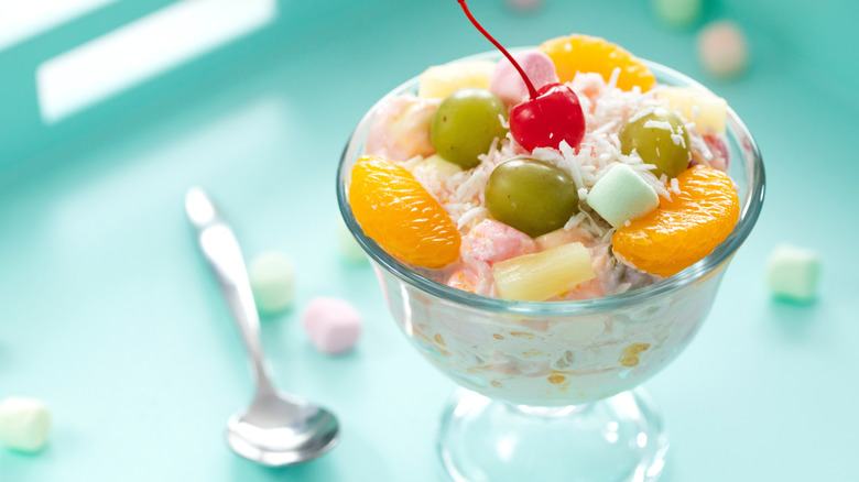 An individual ramekin of ambrosia salad with a cherry on top