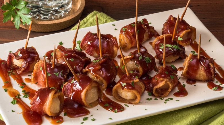 A large platter full of bacon-wrapped, glazed water chestnuts