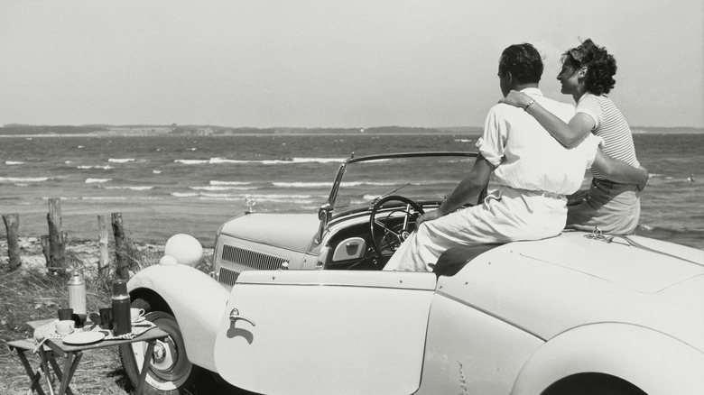 a couple having a picnic by the water in their car