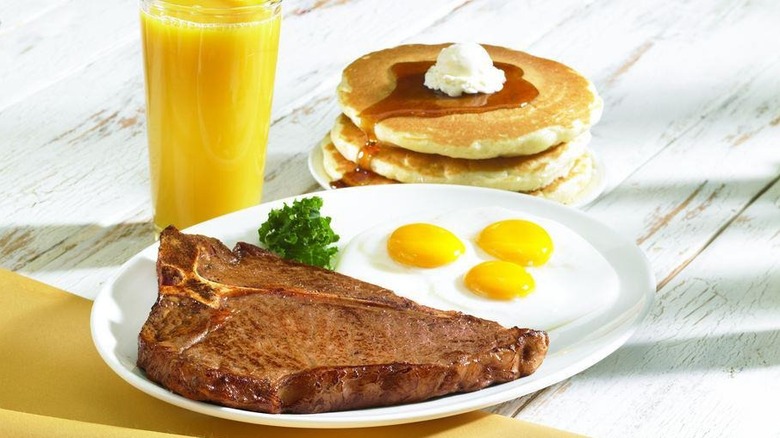 An IHOP T-bone steak dinner with eggs, pancakes, and orange juice