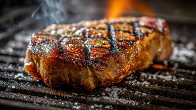A seasoned steak with cross marks on a grill