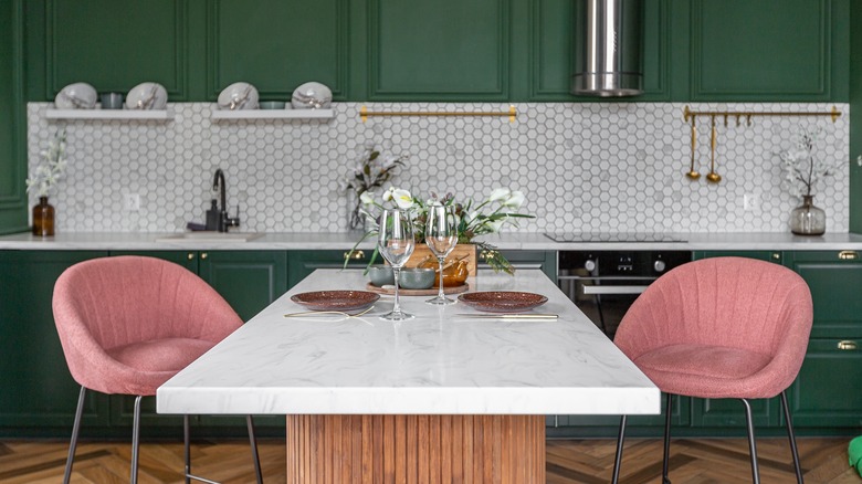 Marble countertops in a kitchen with dark green cabinets