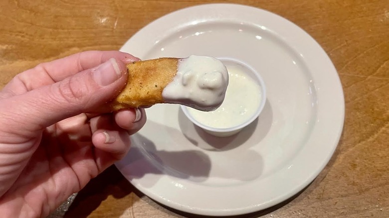 Hand holding steak fry dipped in Texas Roadhouse blue cheese dressing
