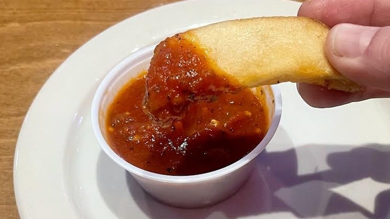 Hand holding steak fry dipped in Texas Roadhouse marinara