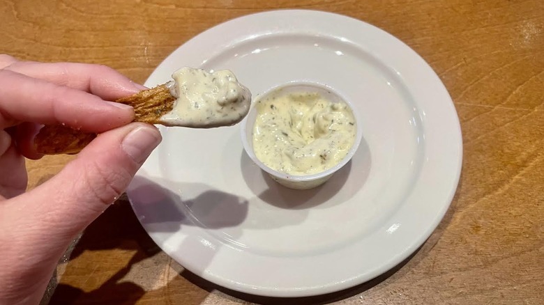 Hand holding steak fry dipped in Texas Roadhouse tartar sauce