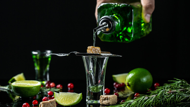 Absinthe being poured over sugar lump into glass