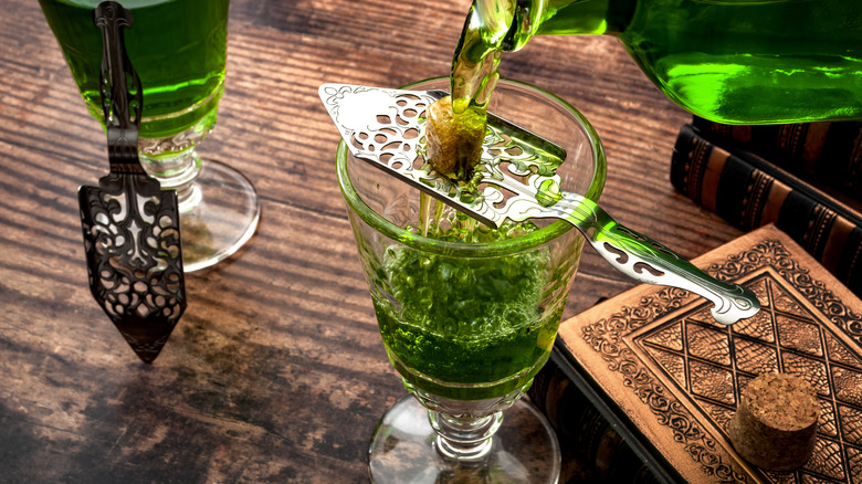 Absinthe being poured over sugar lump into glass