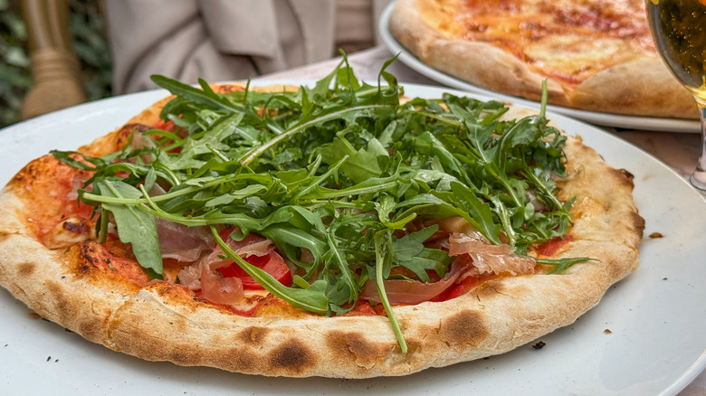 A prosciutto pizza loaded with fresh arugula