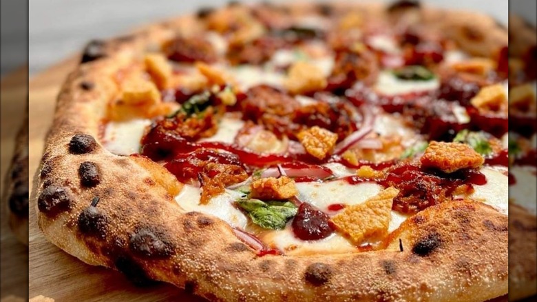 A pizza with pork cracklins, onion, and hoisin duck