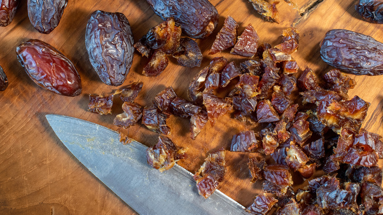 Macro shot of dried Medjool dates being chopped on a wooden cutting board