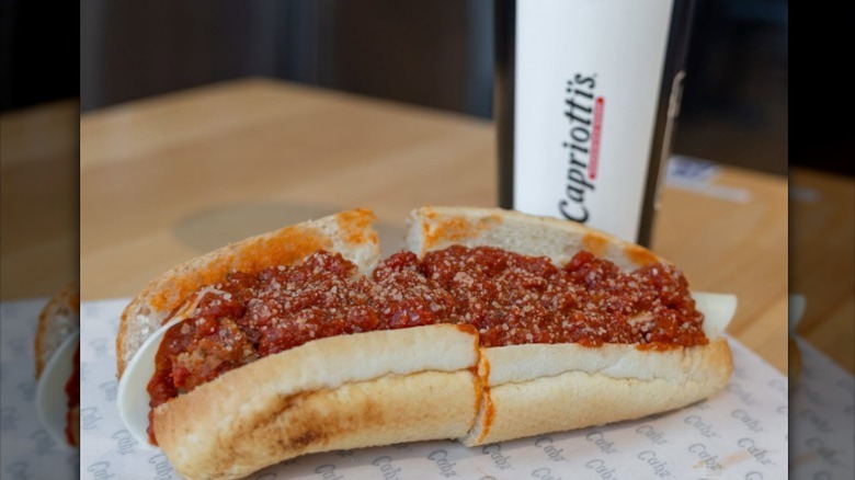 A whole meatball sub sits on a paper wrapper in a Capriotti's Sandwich Shop