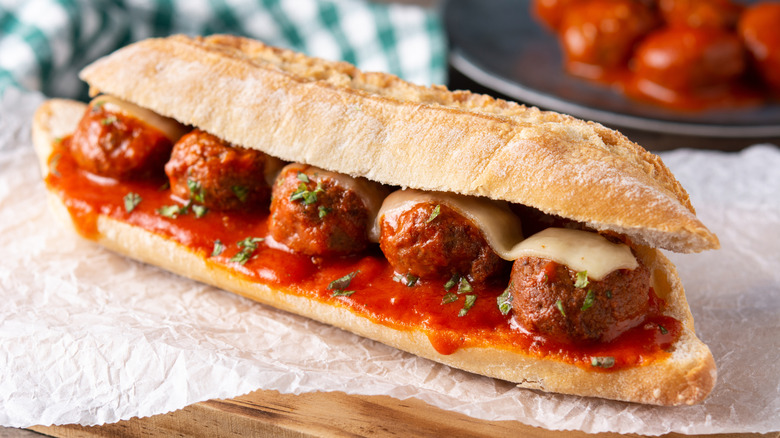 A large meatball sub sits on parchment paper