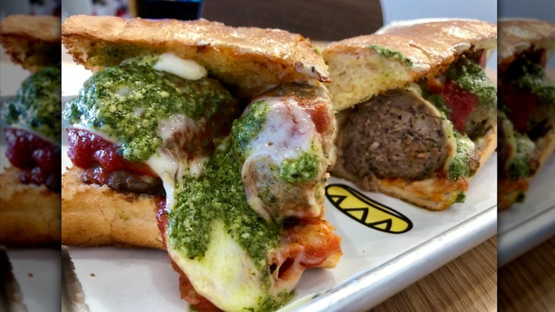 A meatball sub with pesto is cut in half on a paper lined tray in Which Wich