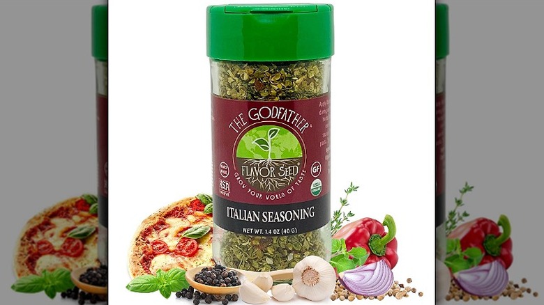 A bottle of Flavor Seed Godfather Organic Italian Seasoning surrounded by spices and herbs against a white background