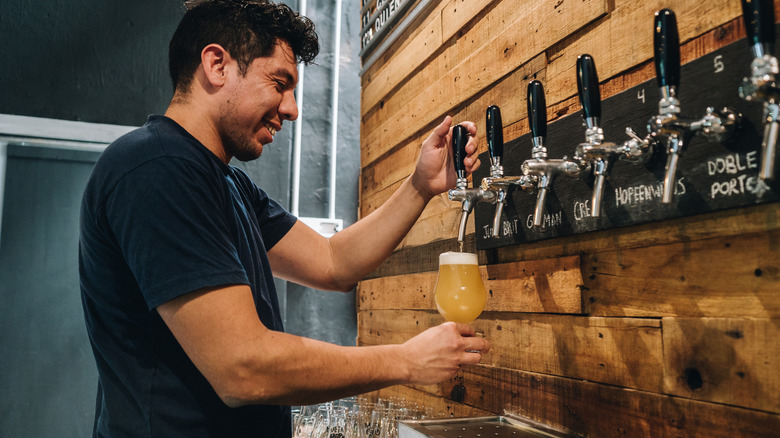 Man pouring beer into glass cup at bar